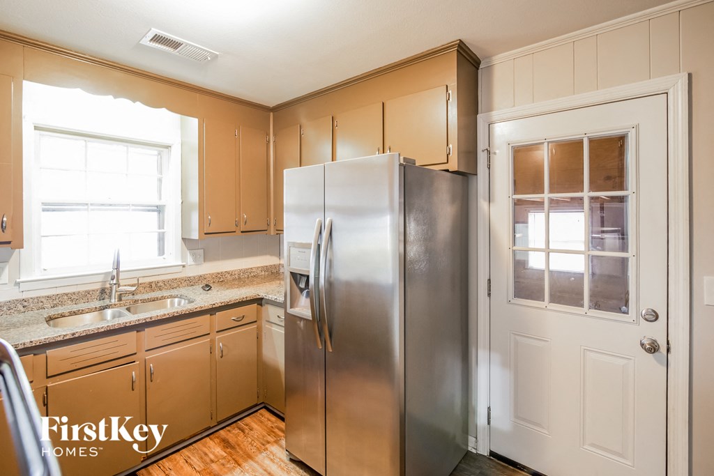A kitchen with wooden cabinets and a stainless steel refrigerator.