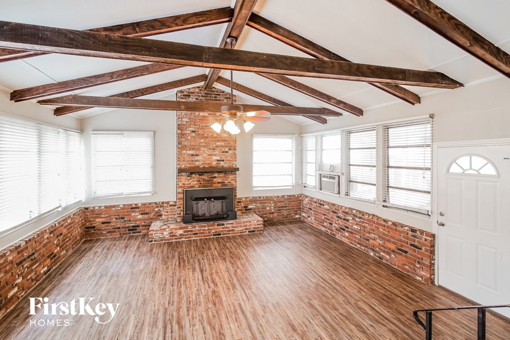 A large open room with a fireplace and wooden beams on the ceiling.