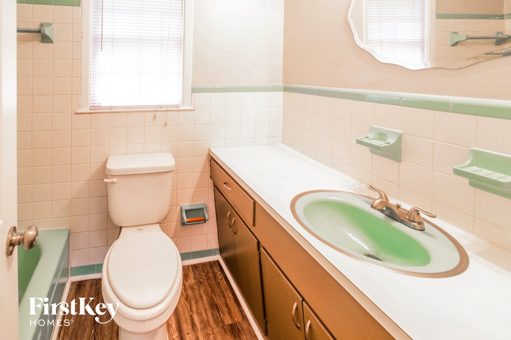 A bathroom with a toilet, sink, and mirror.