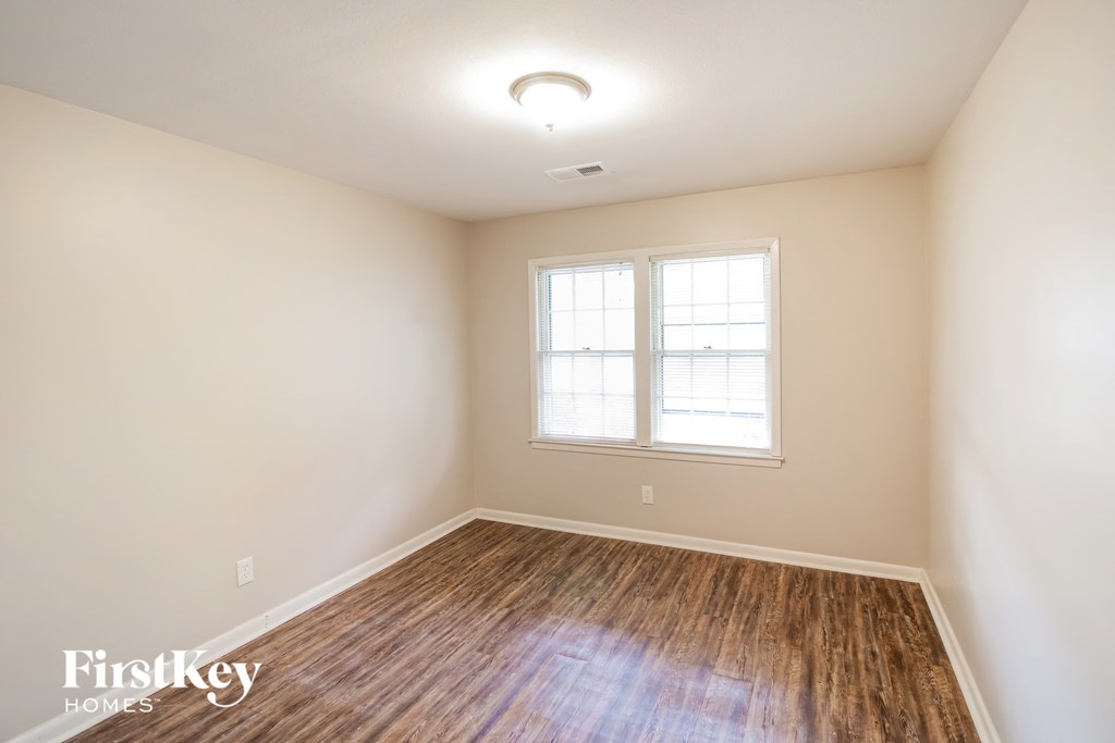 A room with a window and wooden flooring.