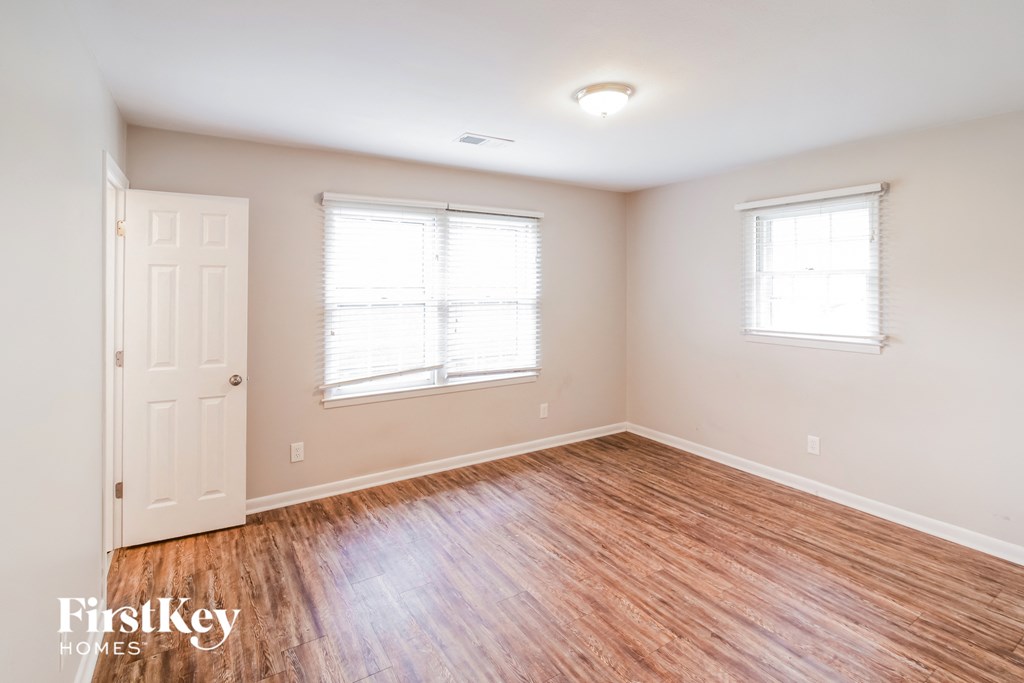 A room with wooden floors and two windows.