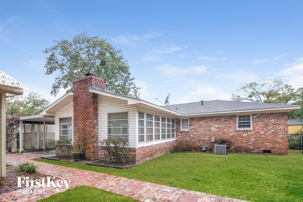 A brick house with a white roof and a green lawn in front.