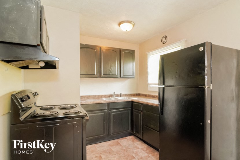 an empty kitchen with black appliances and a refrigerator