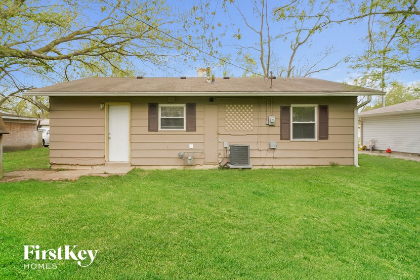a small tan house with a grassy yard and a tree