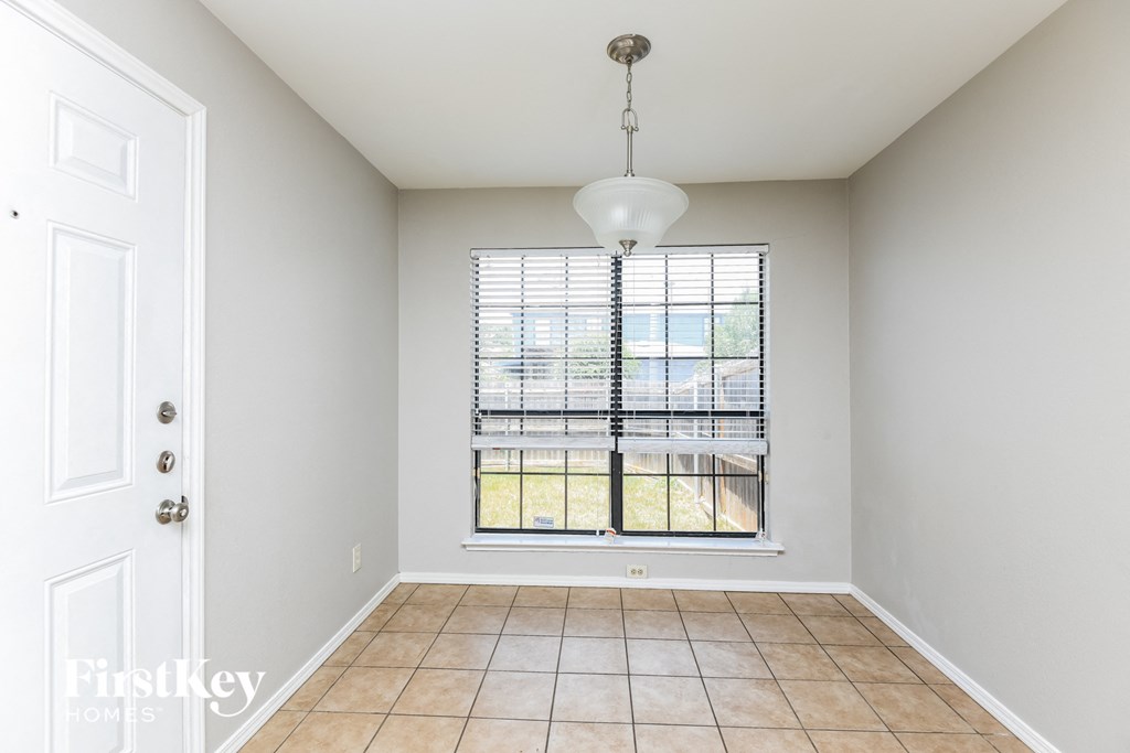 A room with a tiled floor and a window with blinds.