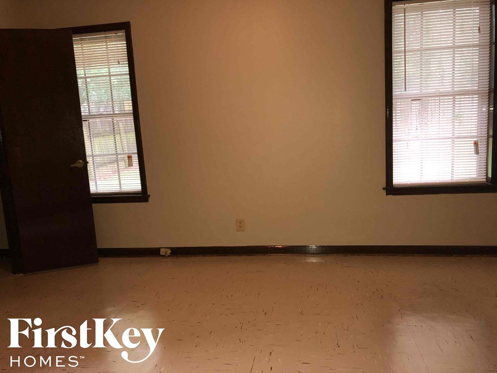an empty living room with two windows and a door