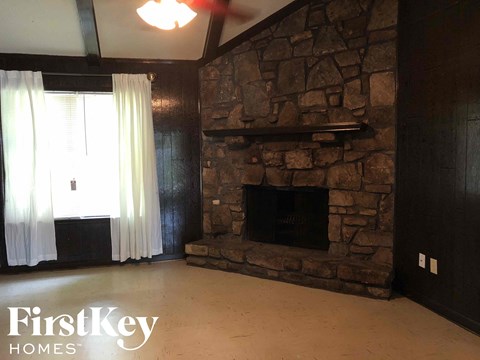 a living room with a stone fireplace and a window