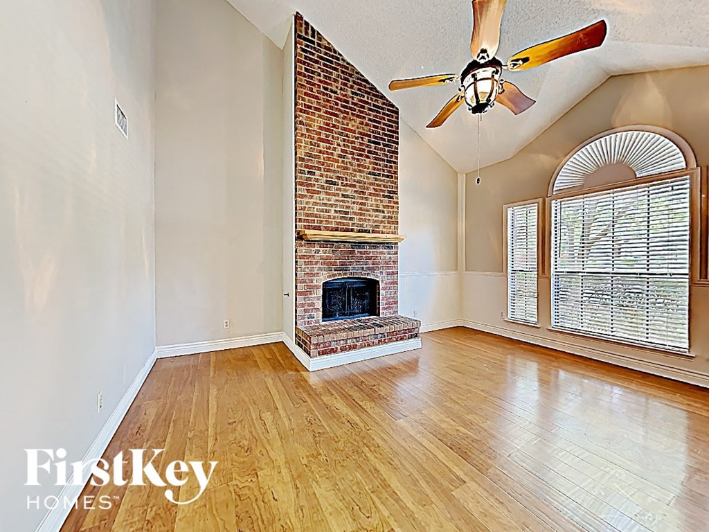 A room with a brick fireplace and wooden floors.