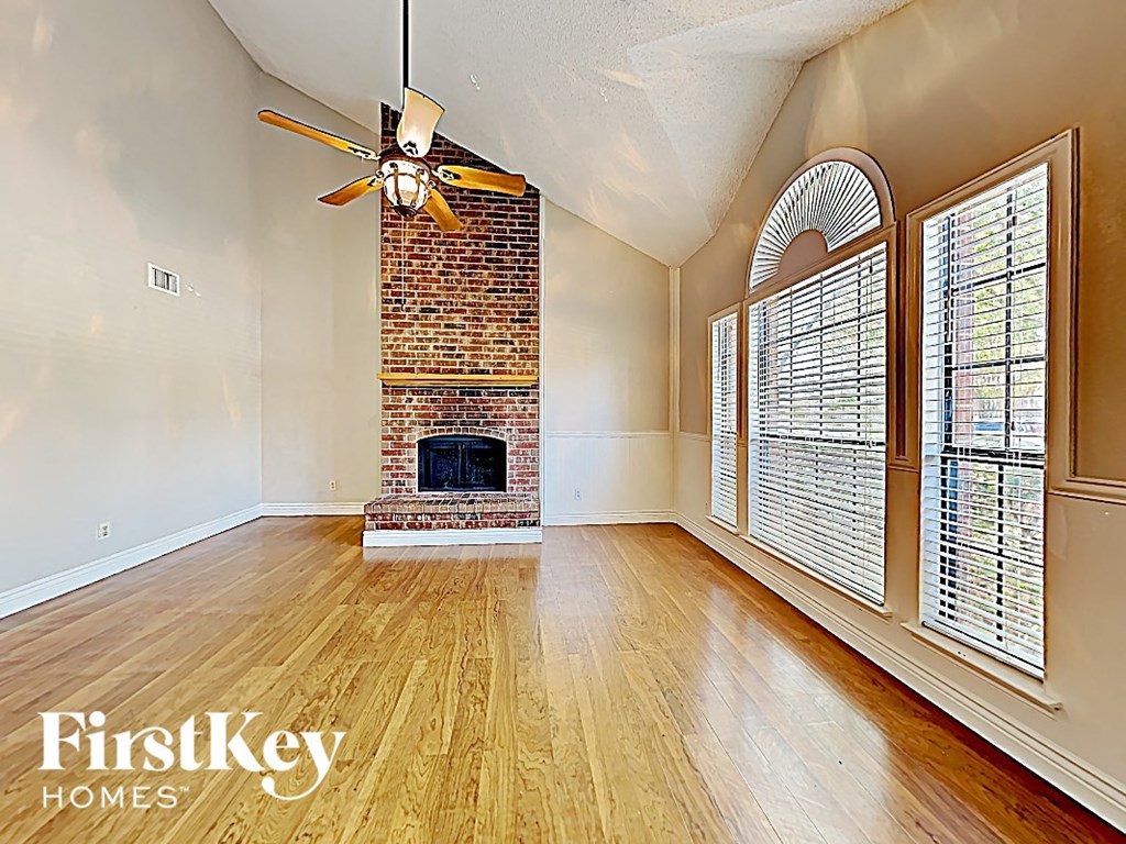 A room with a brick fireplace and a ceiling fan.