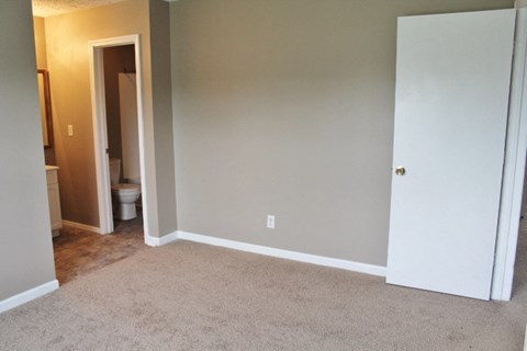a bedroom with a carpeted floor and a door to a bathroom