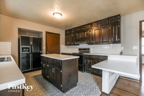 A kitchen with dark wood cabinets and a white counter.
