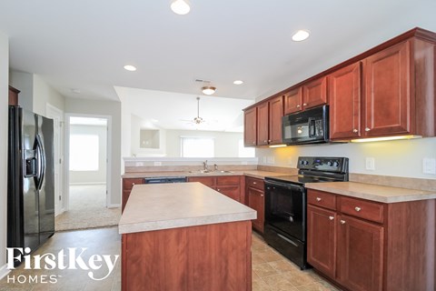 A kitchen with brown cabinets and a black stove top oven.