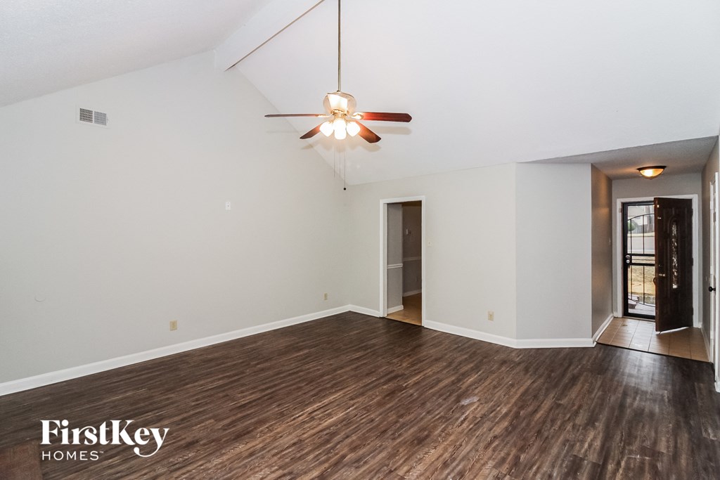 the living room of an empty house with white walls and a ceiling fan