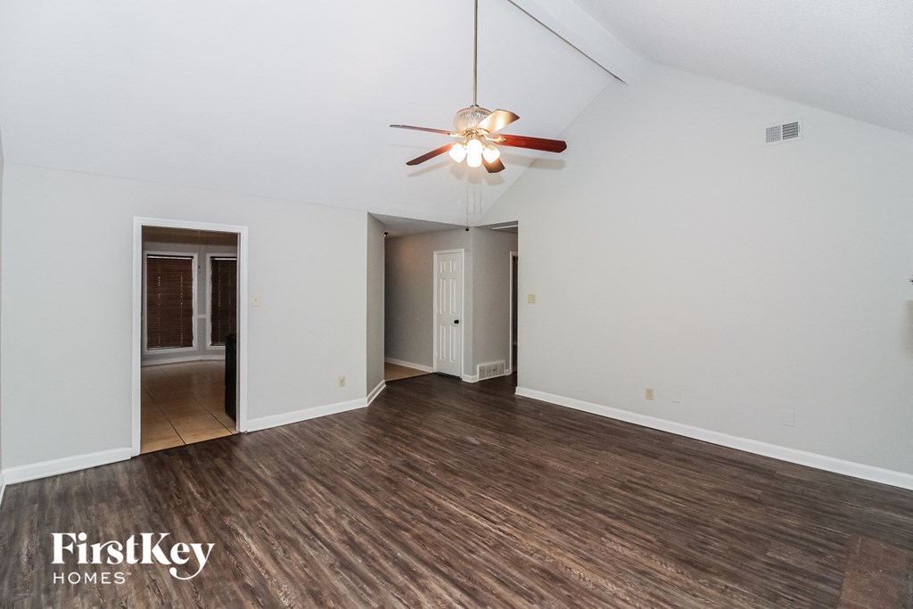 a living room with white walls and wood flooring and a ceiling fan