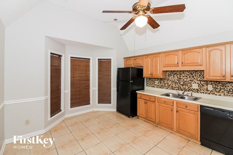 a kitchen with black appliances and wooden cabinets and a ceiling fan