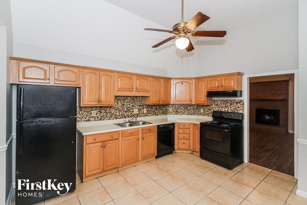 a kitchen with wood cabinets and black appliances and a ceiling fan