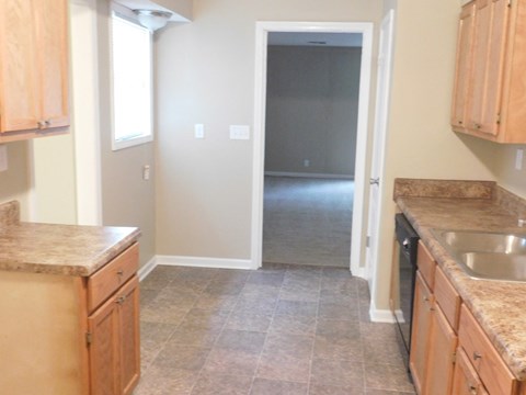 A kitchen with wooden cabinets and a tiled floor.