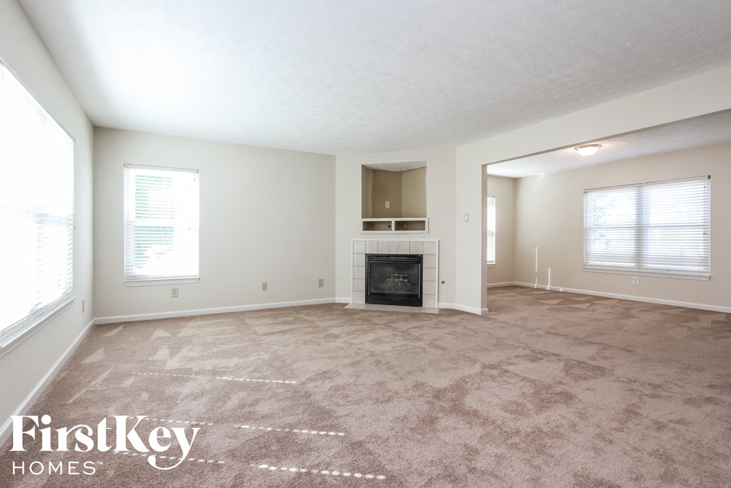 A spacious living room with a carpeted floor and a fireplace.