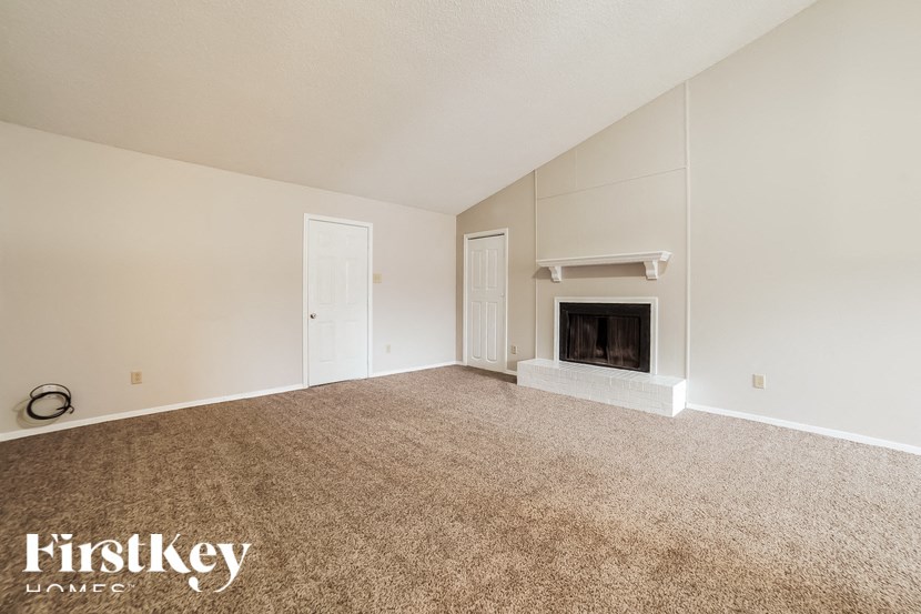 A spacious room with a fireplace and two doors.