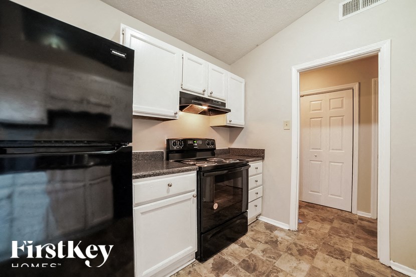 A kitchen with a black oven and white cabinets.