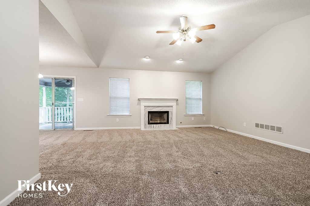 an empty living room with a fireplace and a ceiling fan