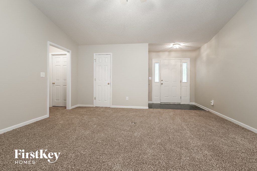 a spacious living room with carpet and white doors