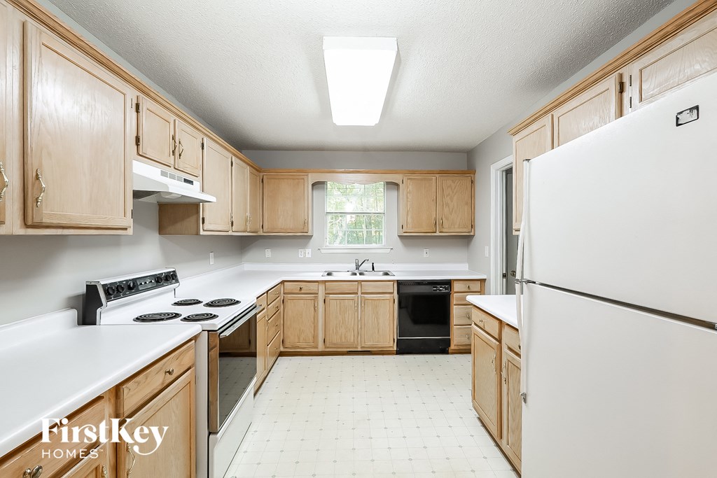 a kitchen with wooden cabinets and white counters and a white refrigerator