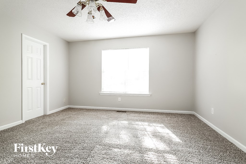 a clean and empty room with a ceiling fan and a window