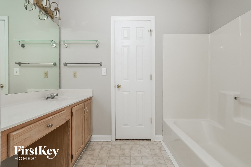 a bathroom with a sink and a shower and a white door