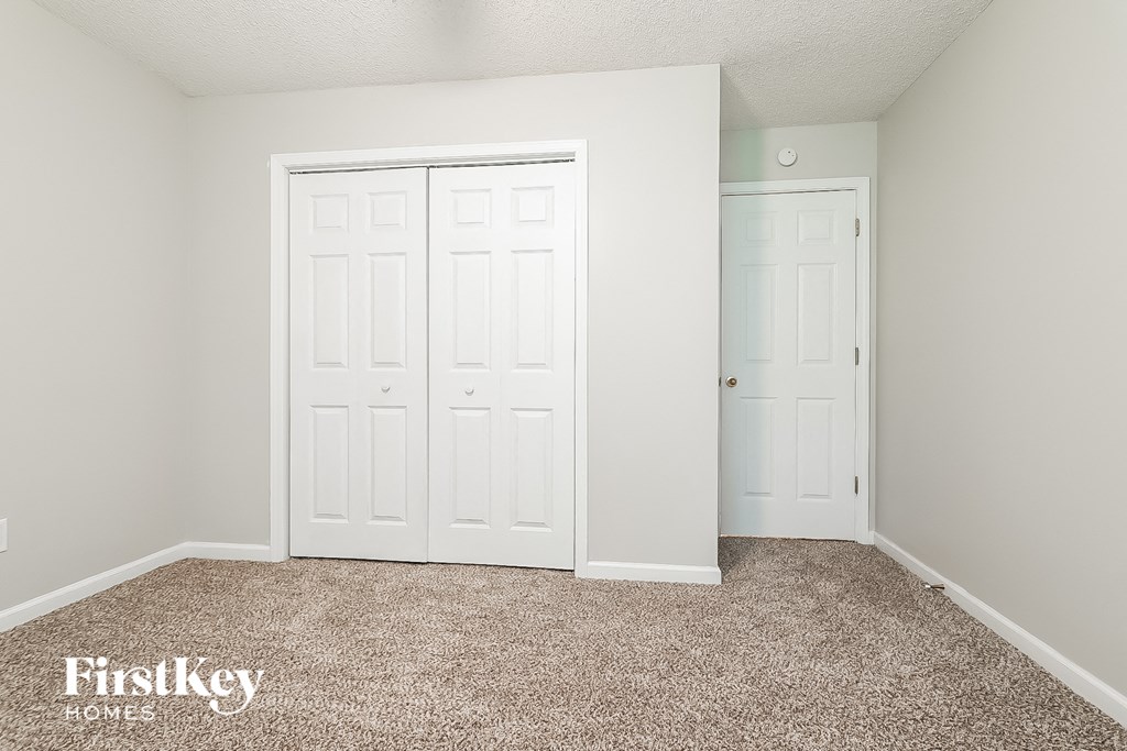 a bedroom with two closet doors and a carpeted floor