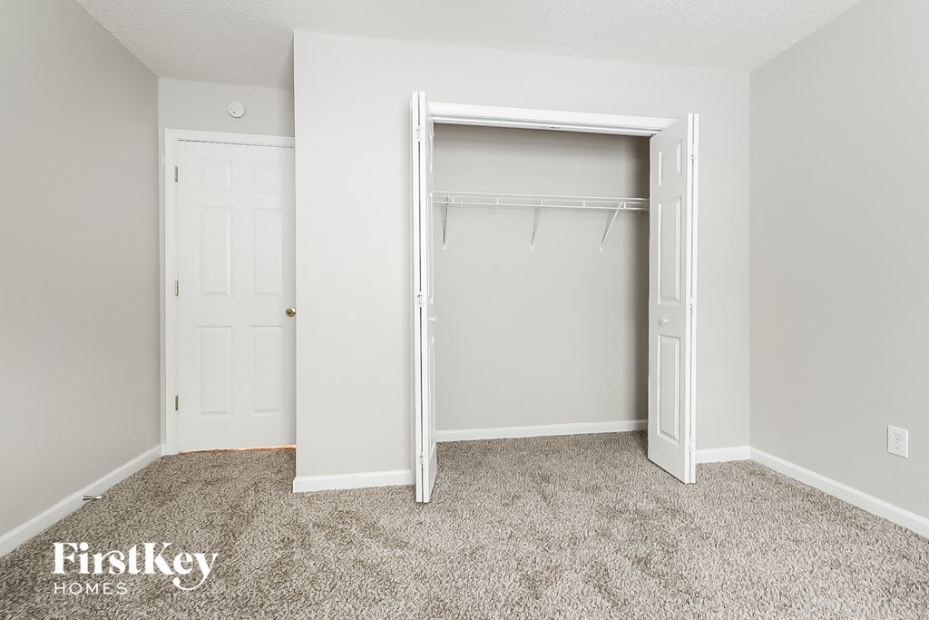 a bedroom with a closet and a white door and a carpeted floor