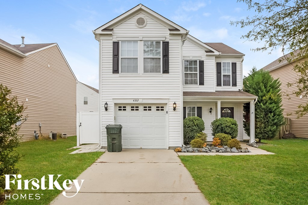 A white house with a garage door and a sign that says "FirstKey Homes".