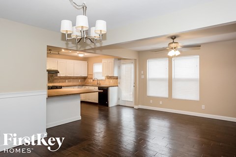 A spacious kitchen and living room with wood floors and a chandelier.