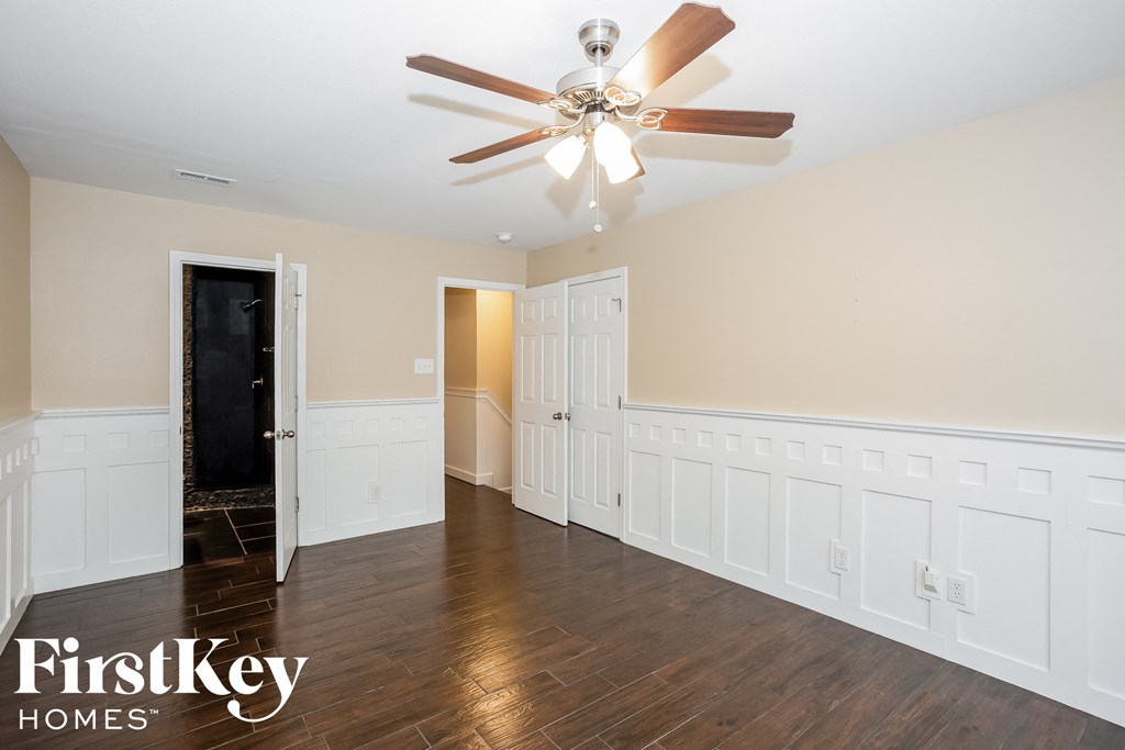A spacious room with a ceiling fan and wooden flooring.