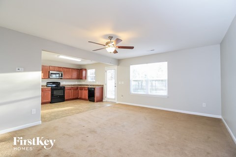 an empty living room and kitchen with a ceiling fan