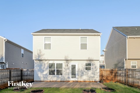 the back of a house with a yard and a wooden fence