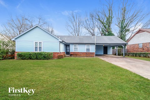 A blue house with a white door and a brick wall.