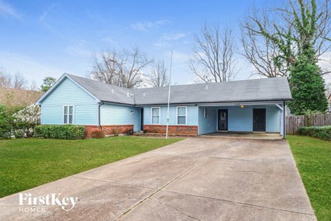 A blue house with a grey roof and a concrete driveway.