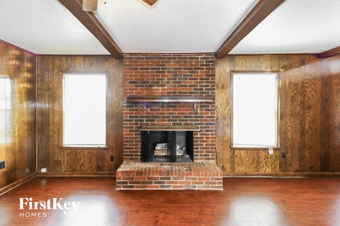 A room with a brick fireplace and wooden floors.
