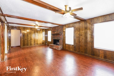 A spacious room with wooden floors and a fireplace.