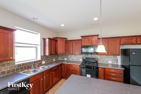 A kitchen with wooden cabinets and a black refrigerator.