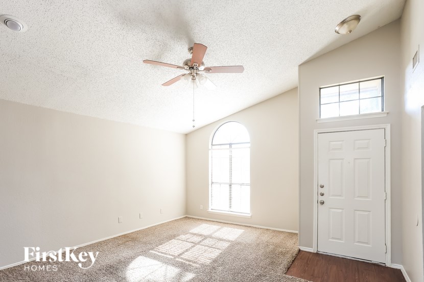 A room with a fan, door, and window.