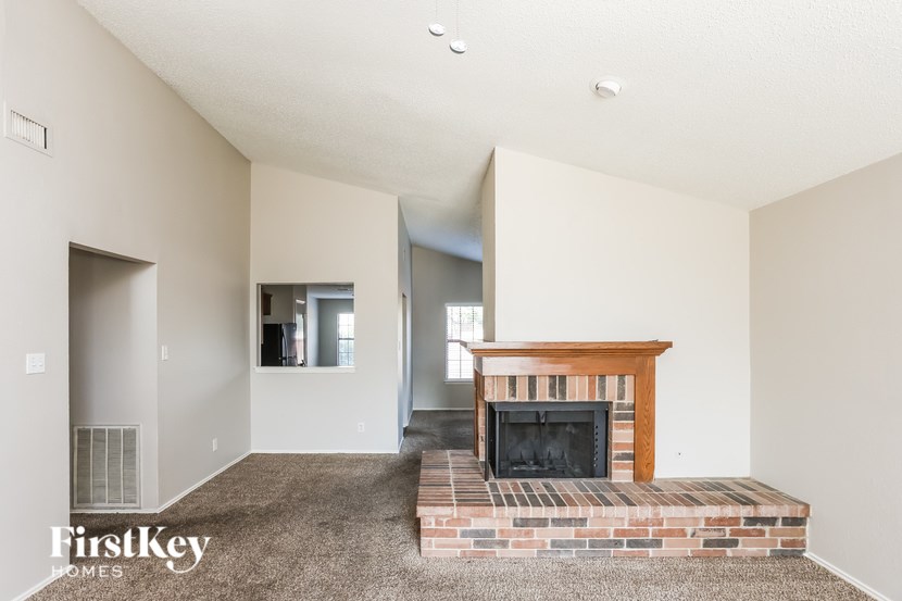 A living room with a fireplace and a carpet.
