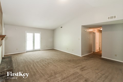 the living room and dining room of a new home with white walls and carpet