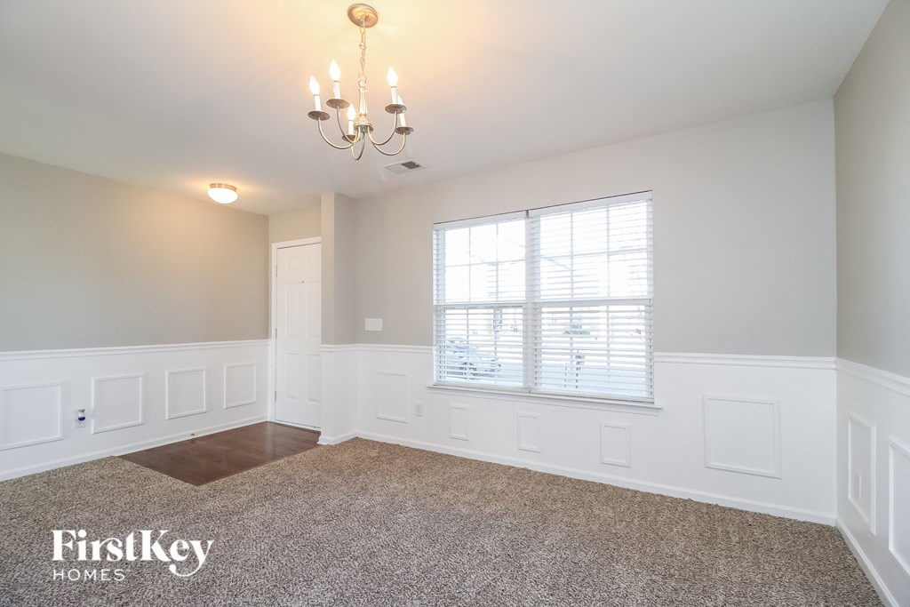 a dining room with white wainscoting and a window