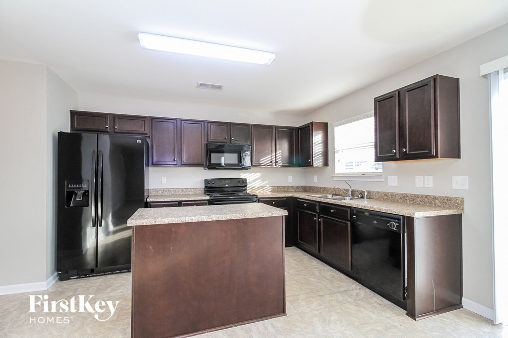 a kitchen with black appliances and granite counter tops and dark wood cabinets
