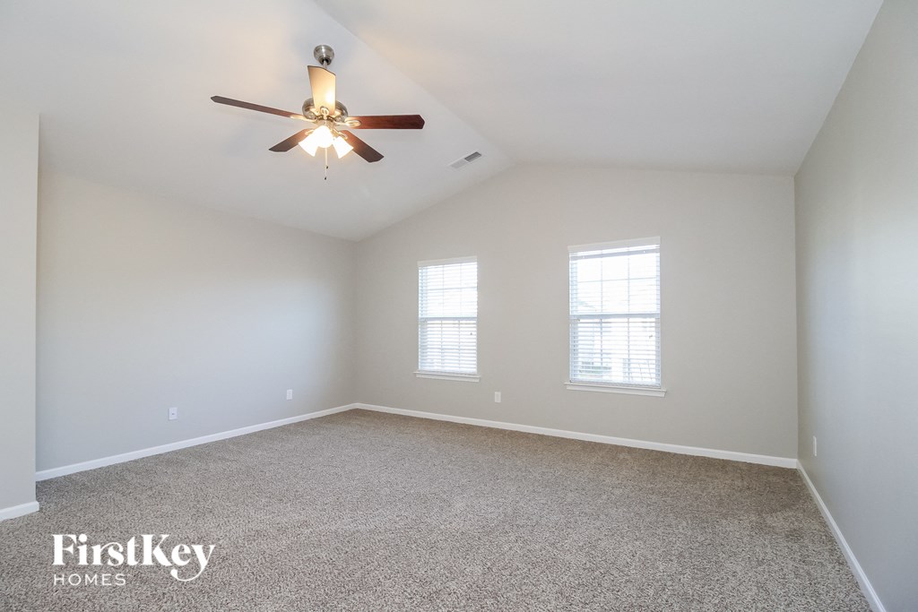 an empty room with a ceiling fan and two windows