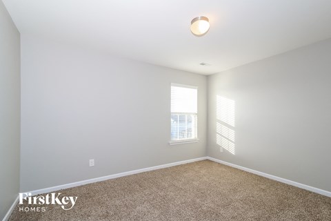 a spacious living room with carpet and two windows