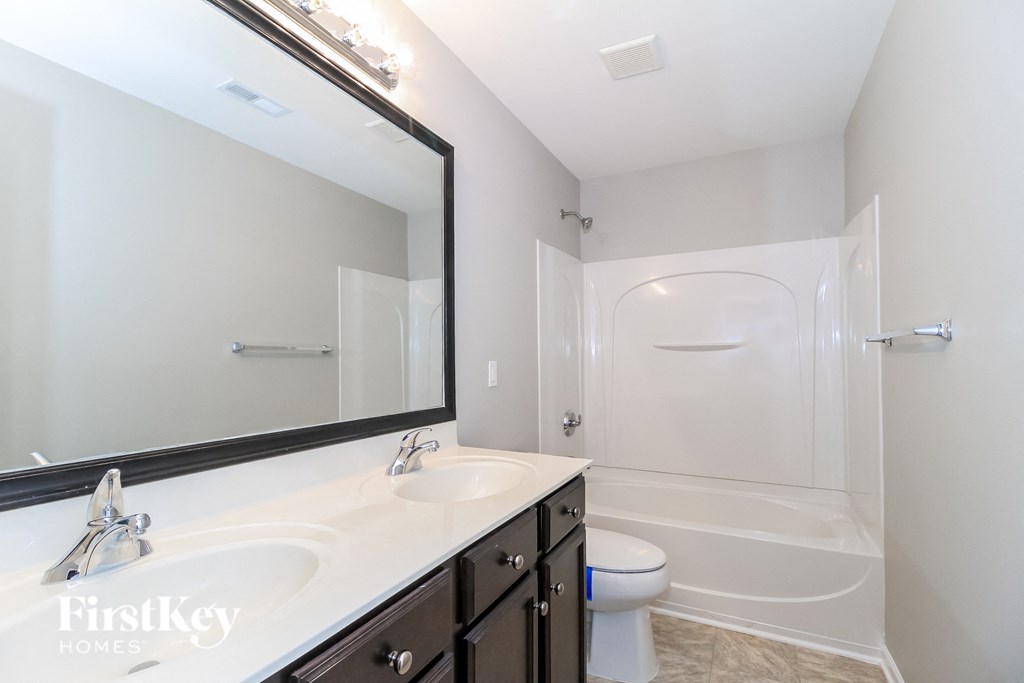 a white bathroom with a large mirror and a white toilet and shower