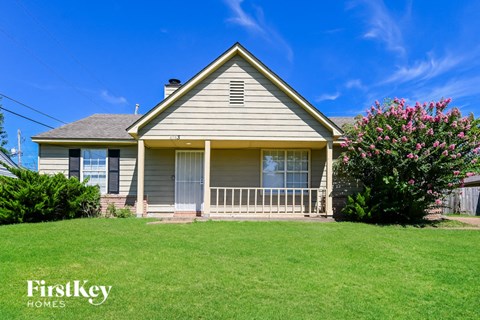 a yellow house with a green lawn and a blue sky
